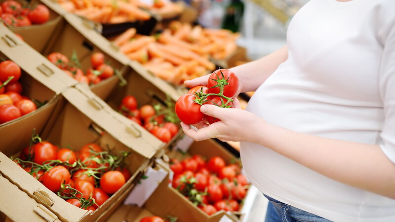 precauzioni pomodori in gravidanza Una donna incinta che sceglie i pomodori